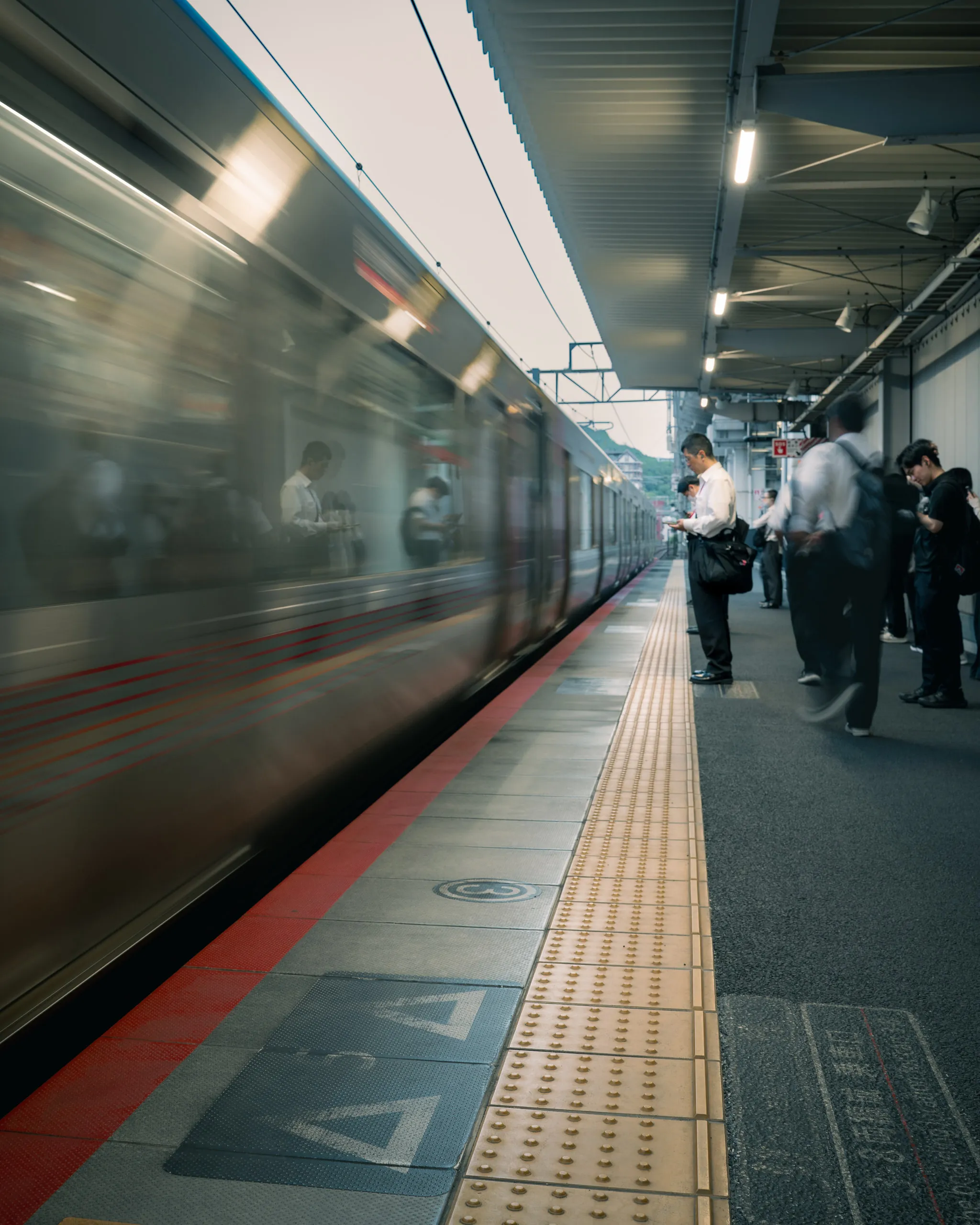 A train blurs into the platform as commuters wait behind the yellow line